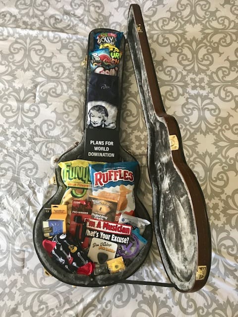 A guitar shaped tin with various items inside of it.